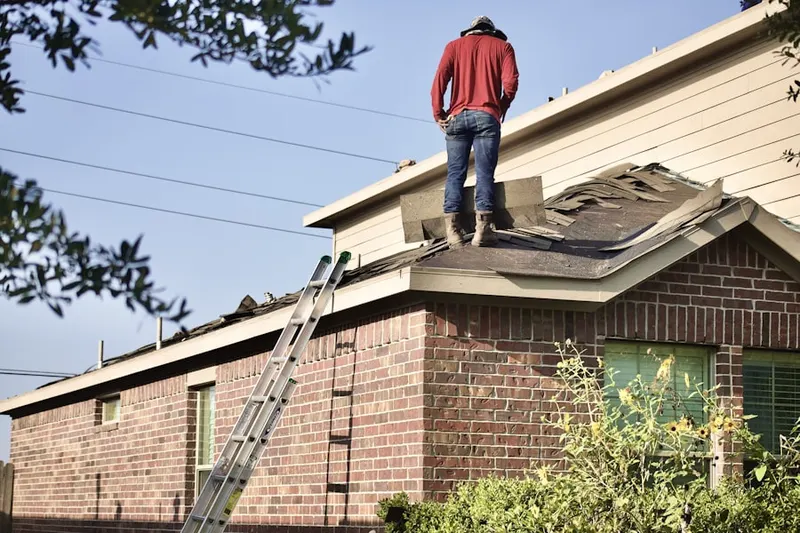 Professional roofer working on a residential roof in Wea